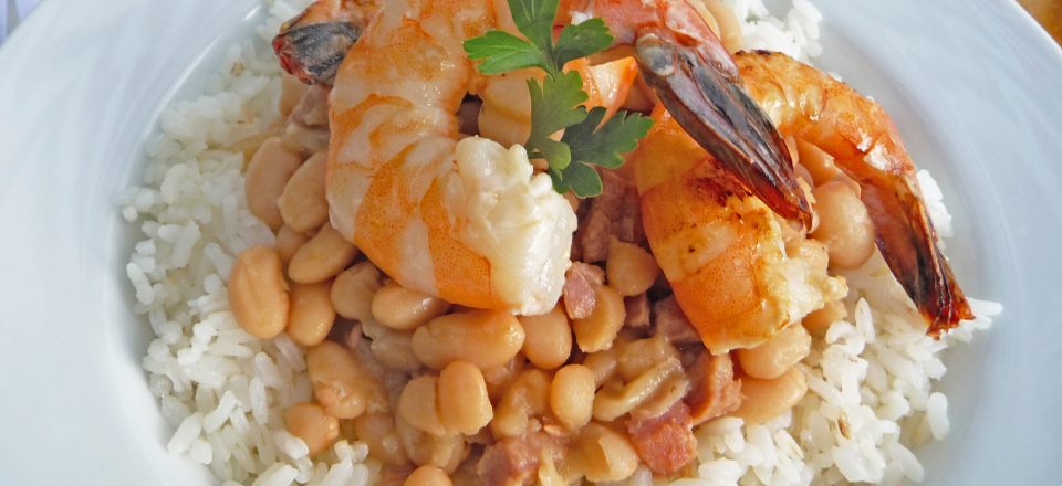 a close up of a plate of new orleans style white beans with a shrimp on top