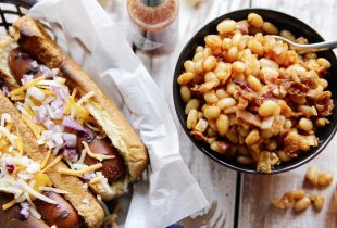 Chipotle Baked Beans in a bowl next to 2 grilled hot dogs