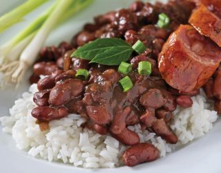 a close up of a plate of red beans and rice with green onions