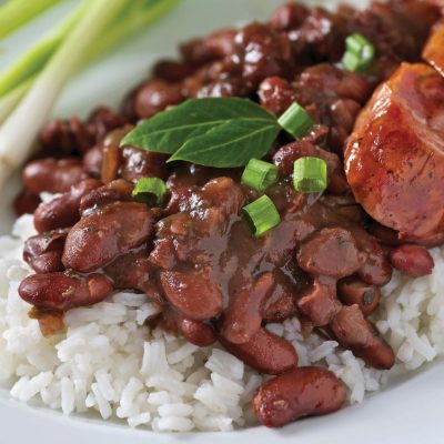 a close up of a plate of red beans and rice with green onions