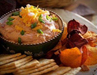 a close up of a plate of skinny red bean dip and a side of chips