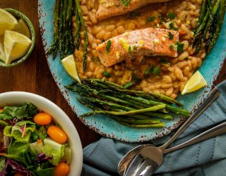 a plate of roasted salmon white beans preserved by lemons next to a small bowl of salad