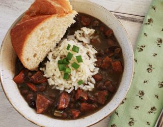 a bowl of crowder peas with smoked pork sausage and green onions with a side of corn bread