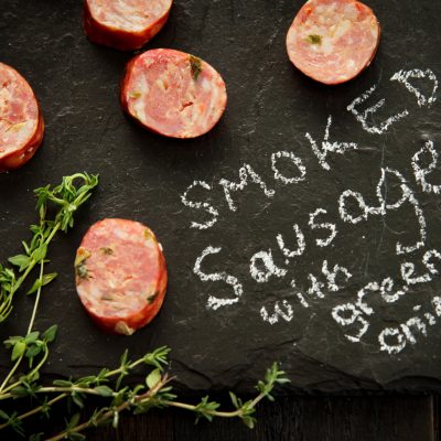 pieces of smoked sausge with green onions on a table with smoked sausage and green onions written on it