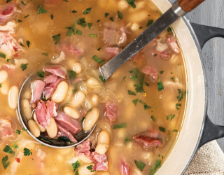 a dutch oven pot filled with white bean stew and hamhock