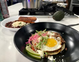 a close up of a dish of red bean huuvos rancheros with a side of red beans and rice with sausage