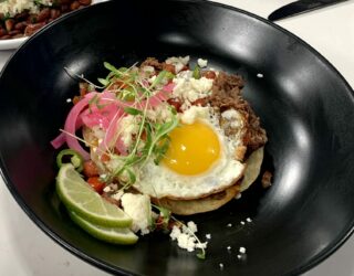 a close up of a dish of red bean huuvos rancheros wwith a side of red beans and rice with sausage