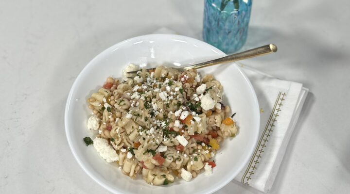 bowl of pasta with lady cream caviar on it on white table with gold fork and blue vase