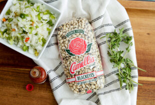 Dried Blackeye peas in Camellia packaging on a kitchen towel next to a white bowl of chopped seasonings