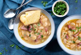 lima beans with meat in a white bowl with cornbread
