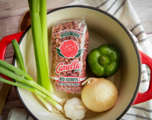 A bowl filled with a mix of beans, chopped onions, and diced celery, showcasing a colorful and nutritious combination.